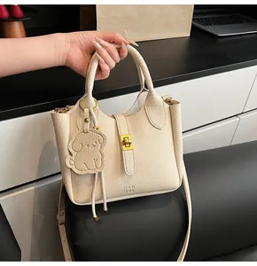 Detail of beige lychee textured bucket bag with gold lock and dog-shaped charm
