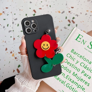 Detail of black iPhone case with 3D red flower pendant and yellow smiley face accent
