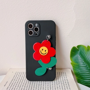 Detail of black iPhone case with a large red sunflower charm and metal chain on a book