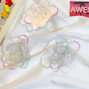 Macro detail of glitter acrylic bear phone grips with colorful outlines on white fabric