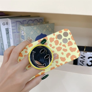 Close-up of yellow cow print phone case with a round smiley face pop socket grip