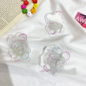 Detailed view of three transparent glitter bear-shaped expanding phone sockets on a book