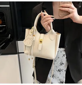 Detail of off-white lychee texture bucket bag with gold twist lock and dog charm
