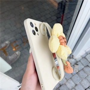 Detail of cream iPhone case with a plush yellow sunflower and integrated wrist strap