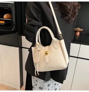 Detail of cream lychee texture leather handbag with gold twist lock and dog charm