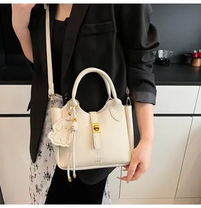 Detail of cream lychee leather bucket bag with gold lock and cute dog charm pendant