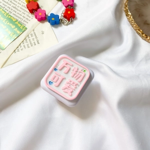 Close-up of cute square phone socket with pink relief text on soft white fabric background