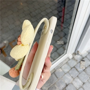 Detail of cream iPhone case featuring a fabric sunflower wrist strap and side button cutouts