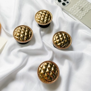 Set of four gold checkered pop sockets with metallic finish on white silk background