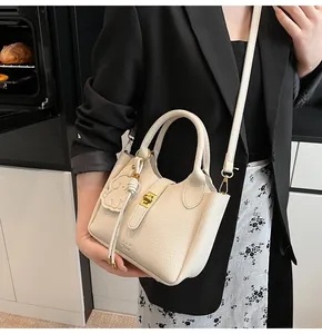 Detail of a beige litchi pattern bucket bag with a cute elephant charm and gold lock