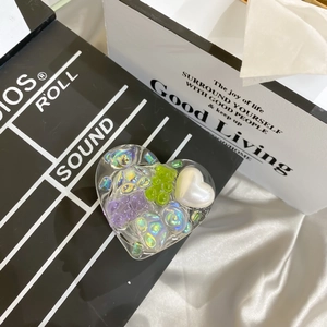 Detail of heart-shaped resin phone grip with 3D green bear and colorful laser glitters