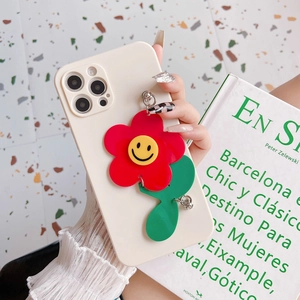 Cream iPhone case with red sunflower charm and smiley face detail on stone background