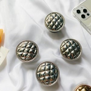 Close-up of four silver grid patterned foldable phone grips on white silk fabric