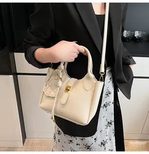 Detail of off-white lychee texture leather bucket bag with gold clasp and chain strap