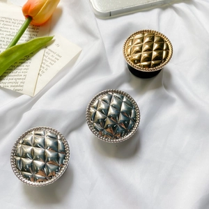 Detail of round quilted grid phone socket stands in gold and silver finish on silk