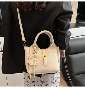 Detail of cream lychee texture leather bucket bag with gold clasp and elephant charm