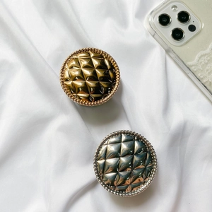 Close-up of gold and silver quilted grid cell phone sockets on white silk fabric