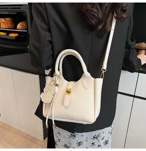 Close-up of white lychee pattern bucket bag with golden buckle and dog charm