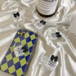 Close-up of heart-shaped acrylic phone grip with black bow detail on checkered case
