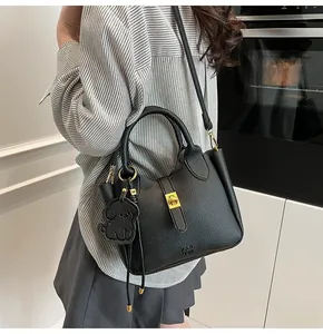 Detail of black lychee grain bucket bag featuring gold hardware and a cute dog charm