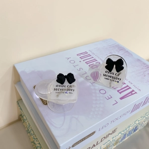 Detail of heart-shaped acrylic phone grip with black bow and artistic text on a book