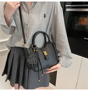 Detail of black lychee grain leather bucket bag with gold clasp and dog charm
