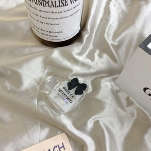Detailed view of a heart-shaped clear phone socket with a black bow on satin fabric