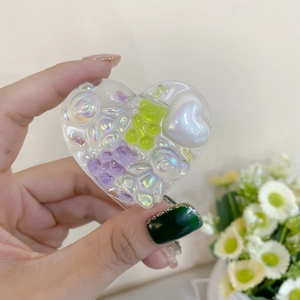 Detailed view of heart-shaped resin phone grip featuring colorful bear and pearl charms