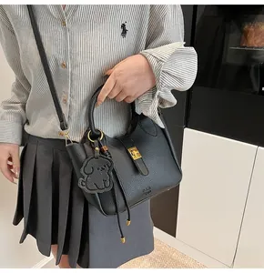 Detail of black lychee grain leather bucket bag with gold clasp and dog charm