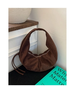 Detail of dark brown suede hobo bag with zip closure and knotted rope handle design