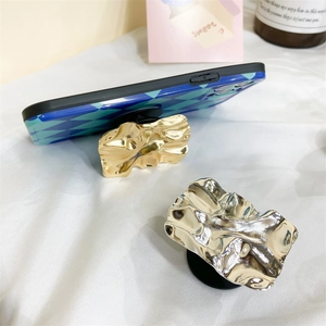 Detail of creative metallic crumpled style phone grip in gold and silver finish
