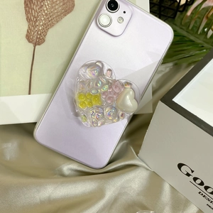 Detail of heart-shaped resin phone grip with colorful bears and pearls on a purple phone