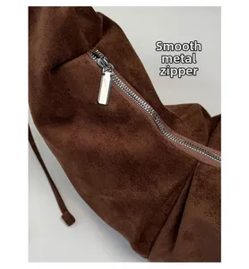 Detail of smooth silver metal zipper on dark brown suede shoulder bag for women