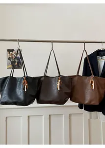 Detailed view of three large capacity tote bags in black, dark brown, and brown colors