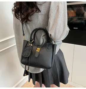Detail of black lychee grain leather bucket bag with dog charm and metal clasp closure