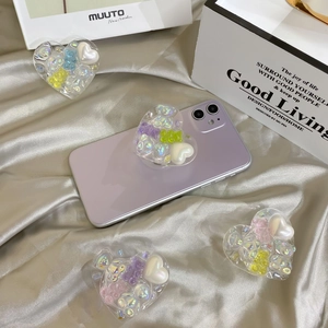 Macro detail of heart-shaped phone grip with colorful pearls and 3D bear decoration