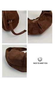 Detailed view of brown suede dumpling bag featuring side drawstring knot and zipper