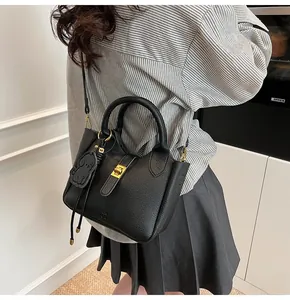 Close-up of black lychee grain bucket bag with gold lock and puppy charm detail
