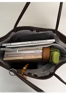 Detail showing the spacious interior of a dark brown leather tote bag with striped lining
