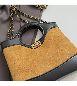 Detail of diamond quilted brown suede bag with golden twist lock and chain strap