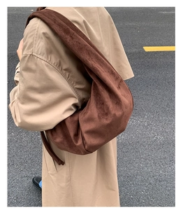 Detail view of large brown suede hobo bag with wide shoulder strap on beige coat