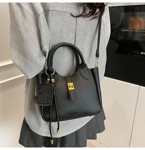 Detailed view of black lychee grain leather bucket bag with gold clasp and dog charm