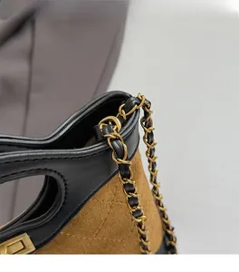 Detail of diamond quilted leather and brown suede stitching with a gold chain strap