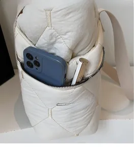 Detailed view of the side zipper pocket on a quilted tote bag holding a phone and lipstick