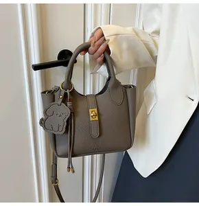 Detail of grey lychee leather bucket bag with gold twist lock and dog charm