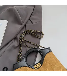 Detail of brown suede quilted handbag with gold hardware and chain strap