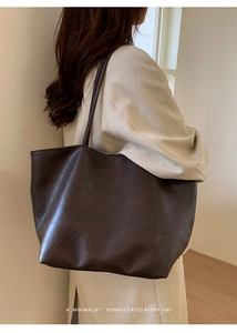 Close-up of minimalist coffee brown leather tote bag with vintage texture on shoulder