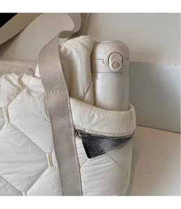 Detail of cream quilted tote side pocket holding a thermos bottle with zipper detail