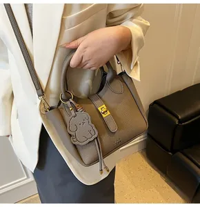Detail of grey lychee leather bucket bag with gold lock and dog charm attachment