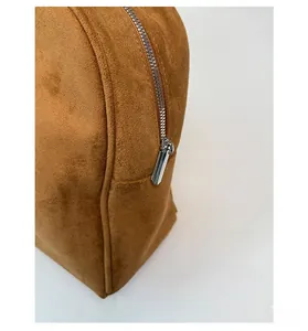 Detalle de cremallera metálica plateada en bolso tote de ante marrón con costura